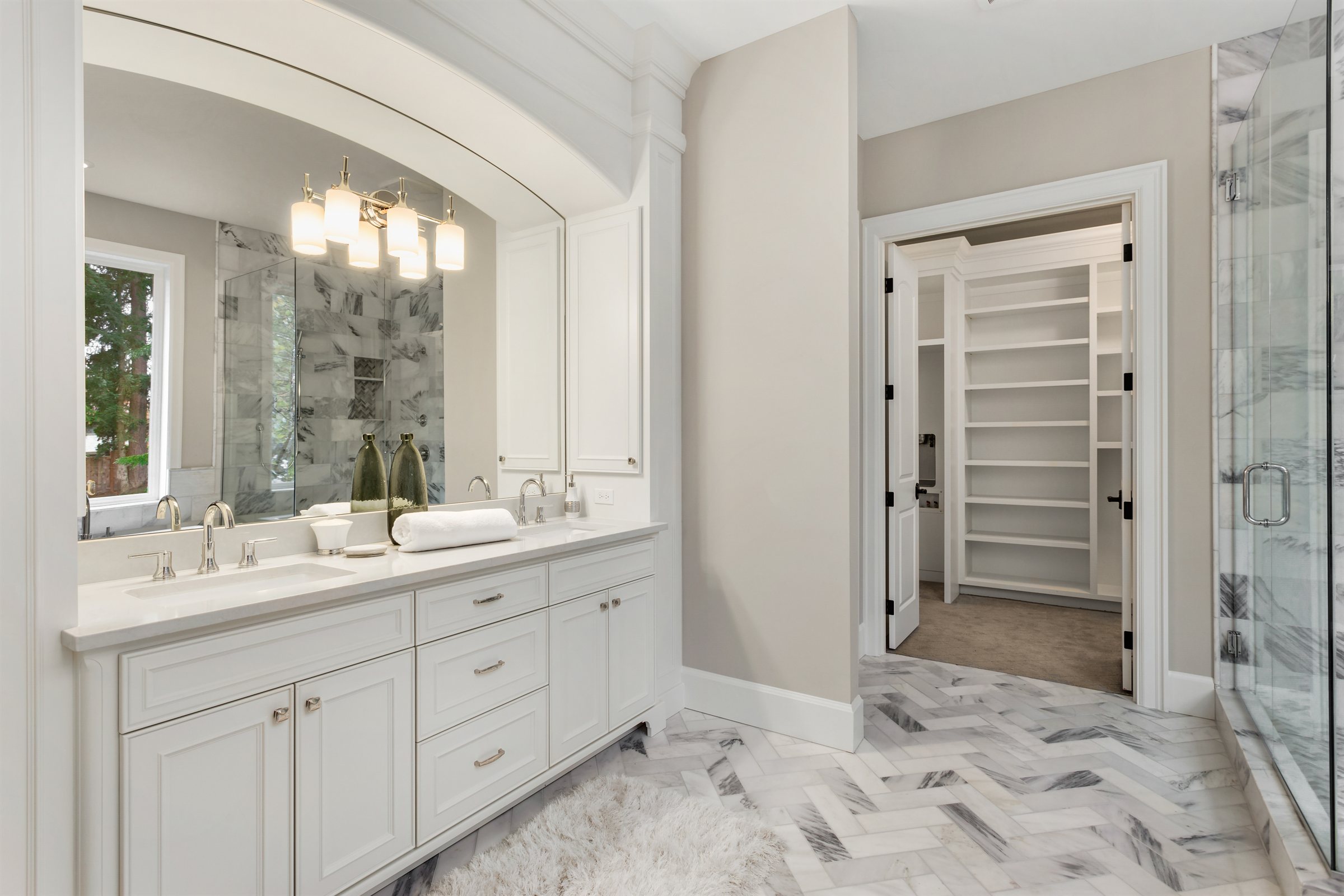 Bathroom remodel with a double vanity and a marble herringbone floor