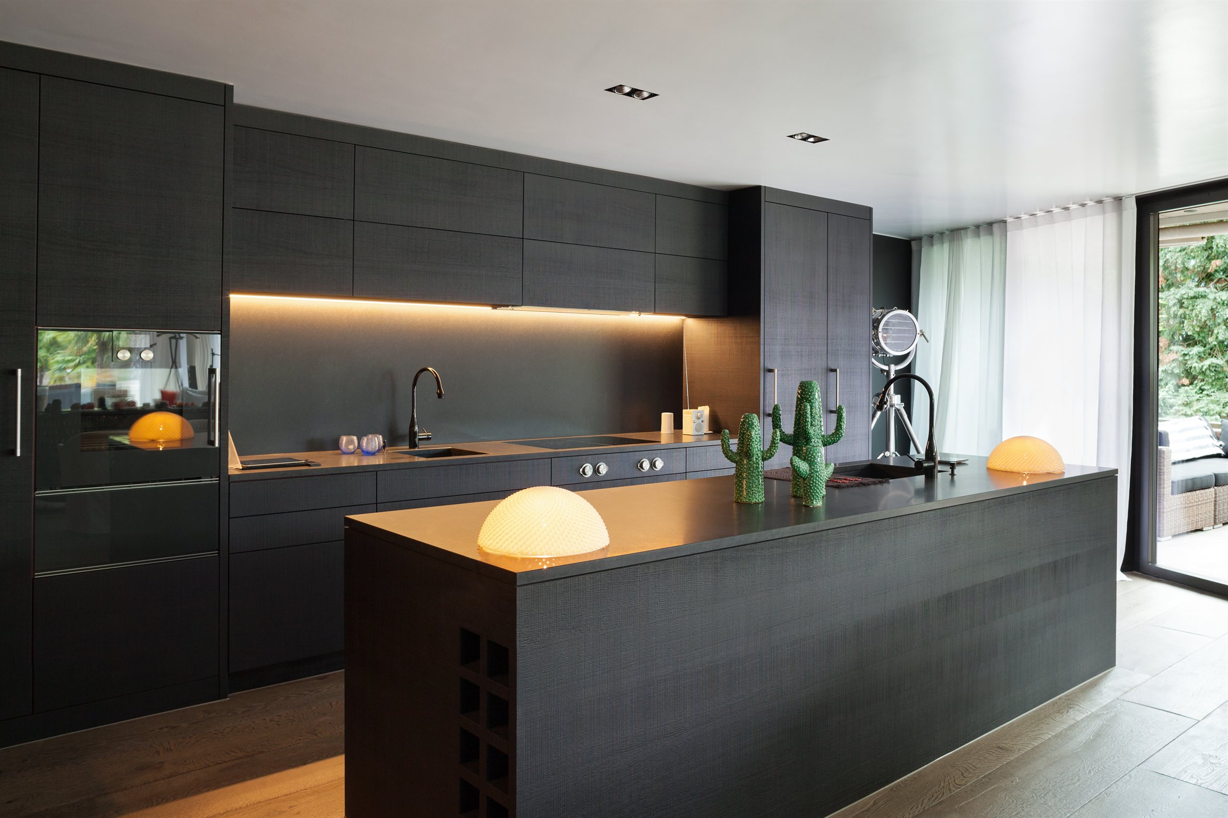 Dark modern kitchen remodel with a long island and integrated appliances