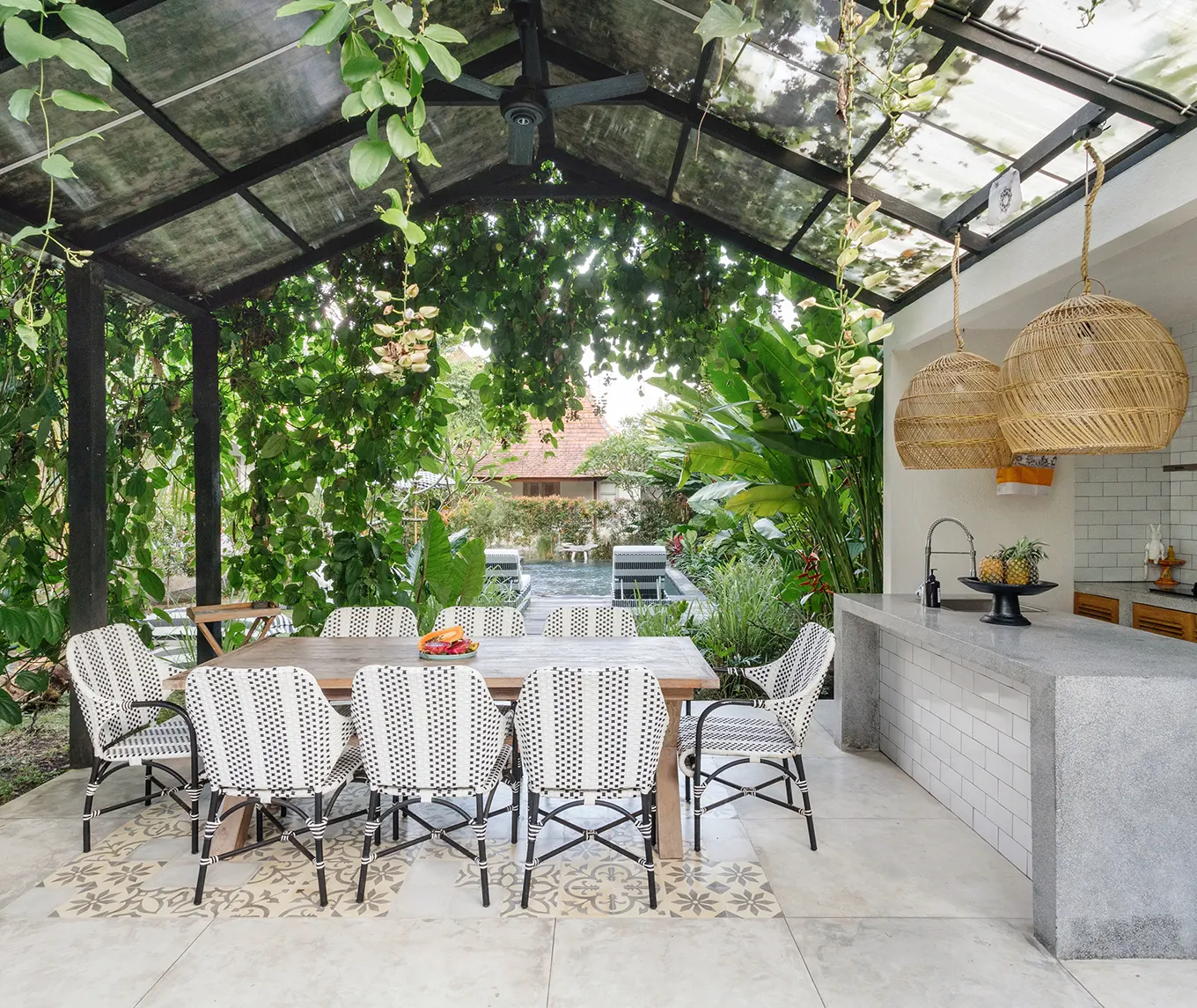 Covered patio with an outdoor kitchen beside a pool